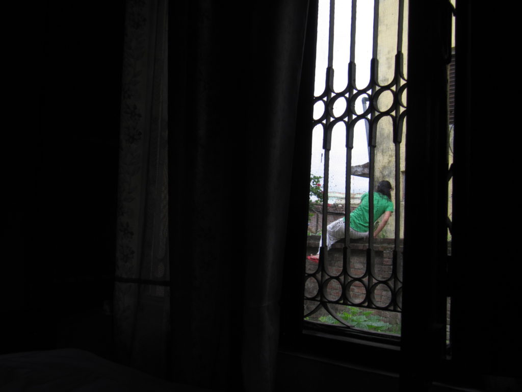 A girl climbing over a wall fence. Asian woman. Dhangadi. Nepal