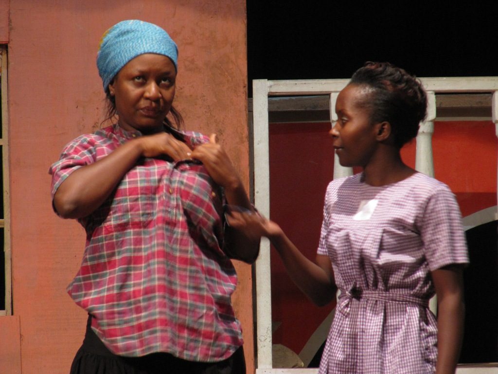 Two actresses perform on a theater stage in Kampala