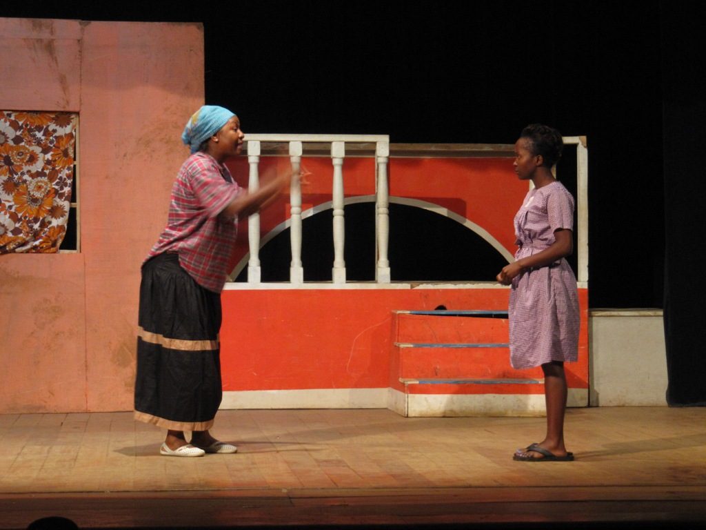 Two actresses perform on a theater stage in Kampala