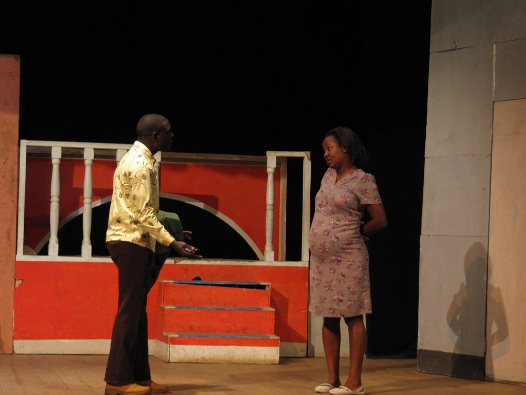 Two actors, a male and a female, perform on a theater stage in Kampala