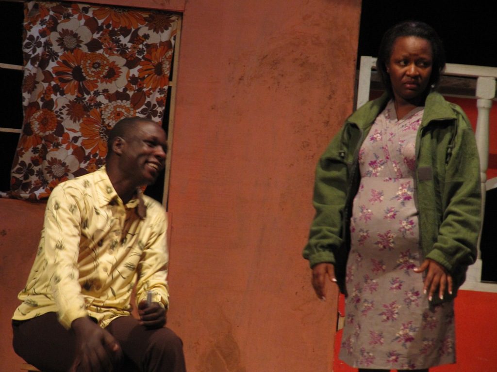 Two actors, a male and a female, perform on a theater stage in Kampala