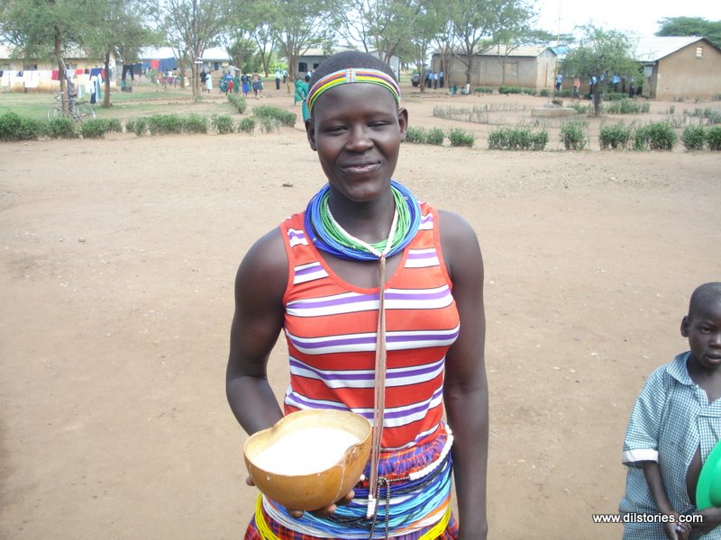 A school girl in Moroto, in a traditional dance costume, holds a calabash of porridge for lunch