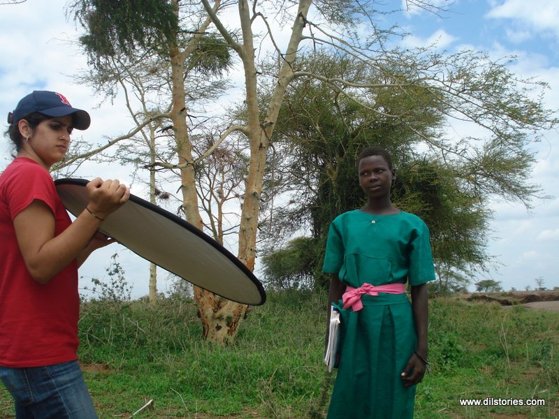 A camera assistant holds a reflector to light up a subject during the making of a documentary film