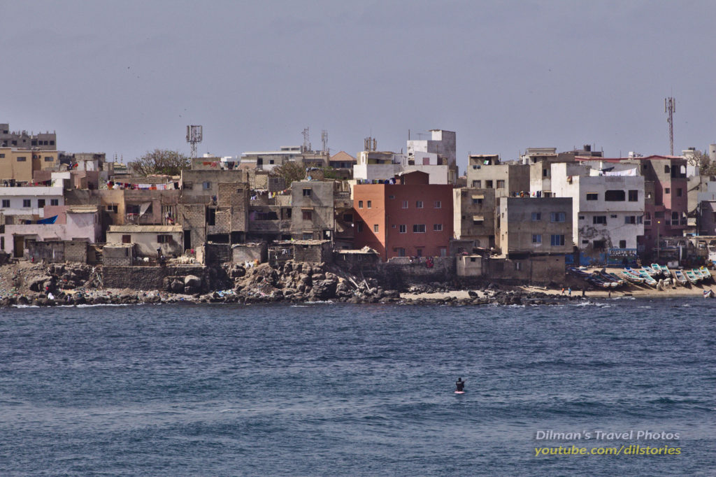 Buildings crowded on the coast. A small fishing boat in the foreground.