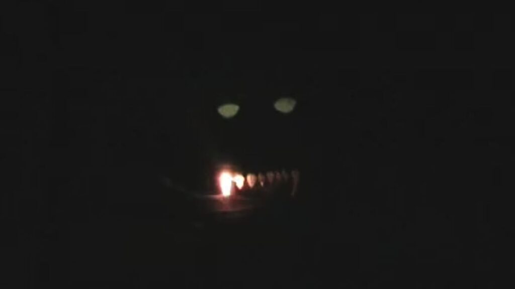 A screenshot of a monster in a film, the effect made by cutting cardboard into shapes for eyes and teeth, and shining a light from behind it.