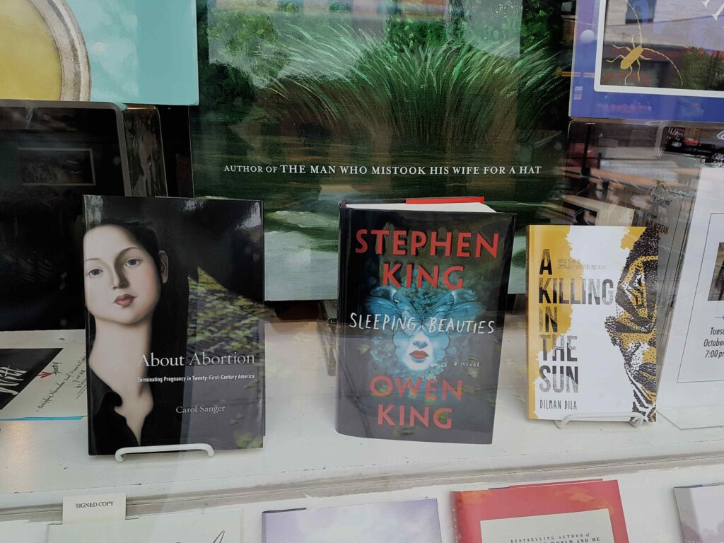Three books on display at a bookshop window.